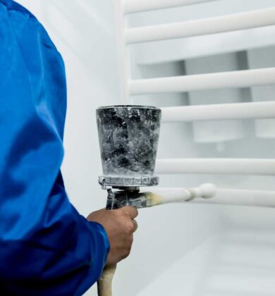 Worker performing powder coating of metal details at factory