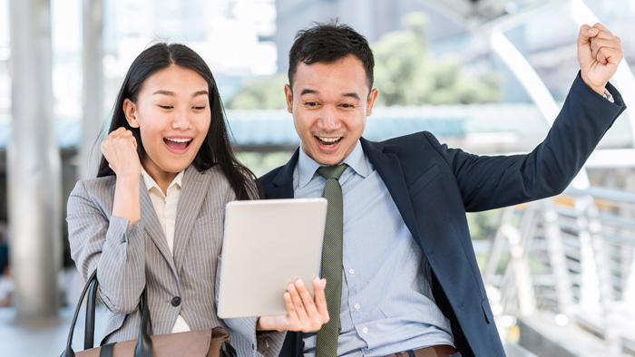 Happy colleagues using a tablet outdoors